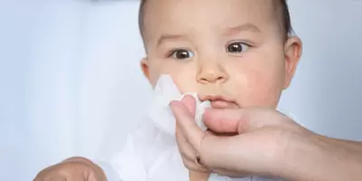A baby having it's face wiped with a baby wipe
