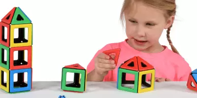 A young girl playing with magnetic building shapes