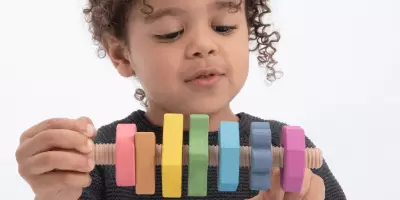 A boy playing with a wooden toy with twisting cogs and bolts
