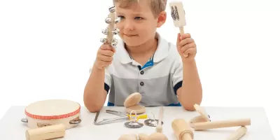 A boy sat at a desk playing with an instrument percussion set