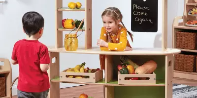 A girl playing with a small jar of chocolate spread, a role playing toy