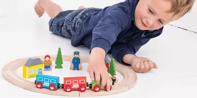 A young boy playing with a wooden train set
