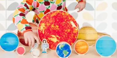 A young boy playing with a set of wooden solar system discs