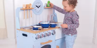 A girl playing with a wooden kitchen