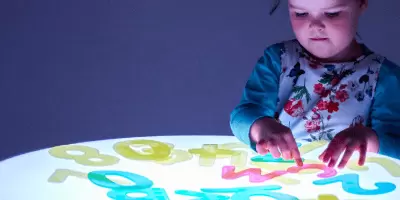 A girl playing with translucent letters on a sensory light table