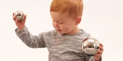 A boy holding silver reflective balls that make a sound