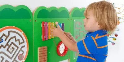 A boy playing with a wooden crocodile wall game
